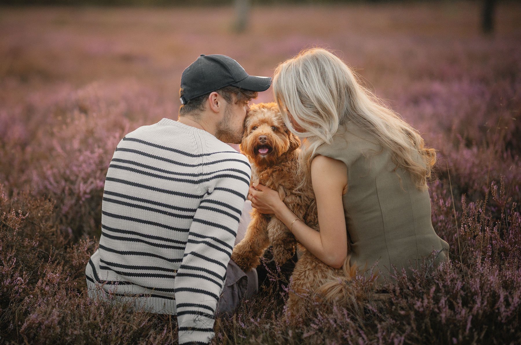 A man and a woman hug their dog during a photo walk in the forest.